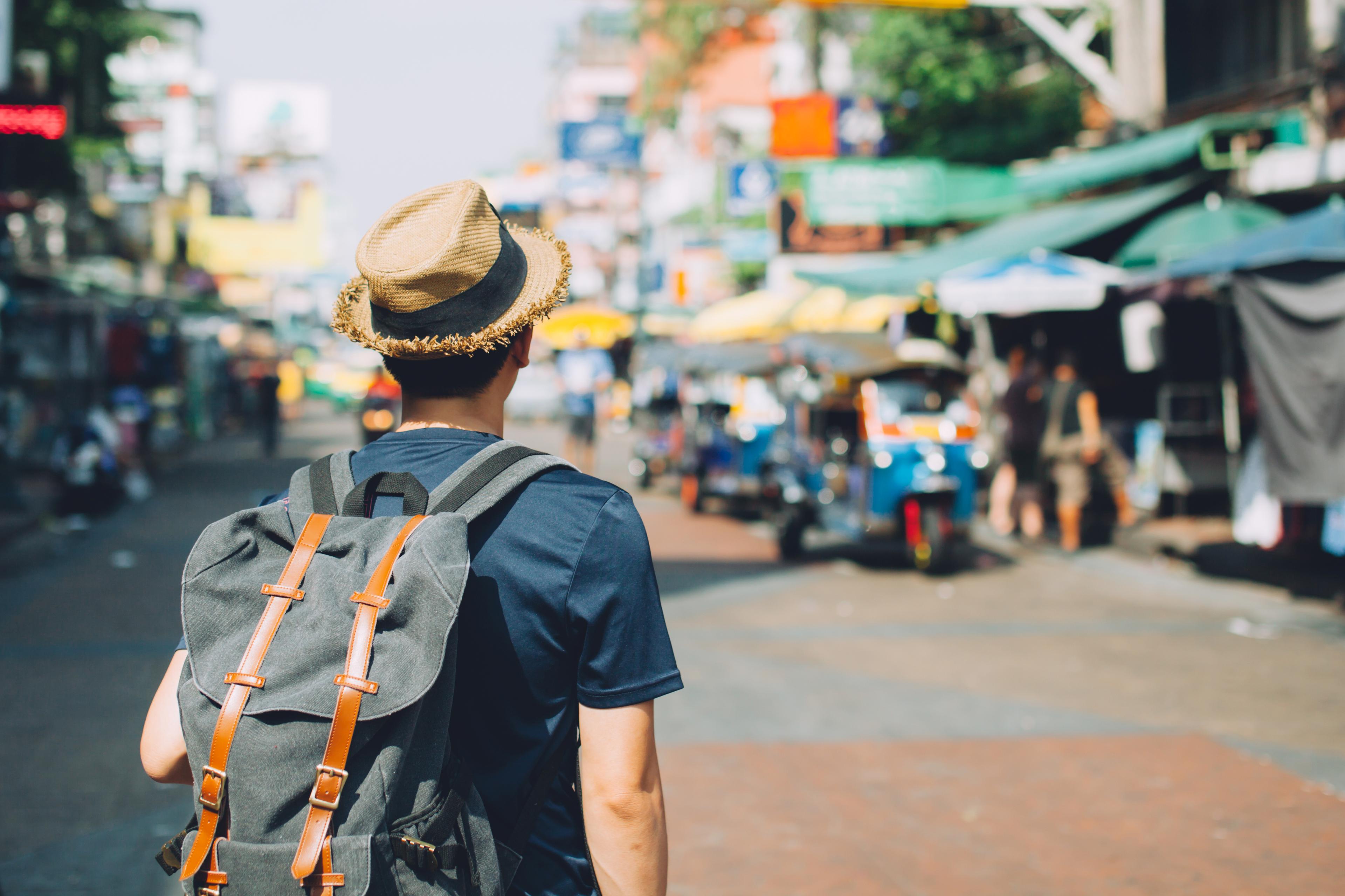 A tourist with a backpack walking through an outdoor market 